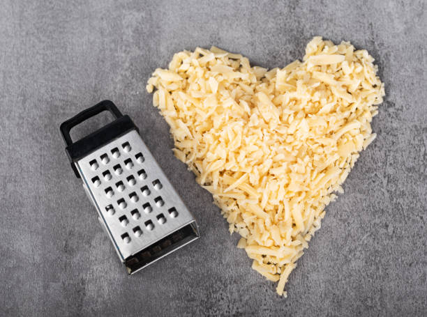 A heart shaped pile of grated parmesan and a small grater. top view